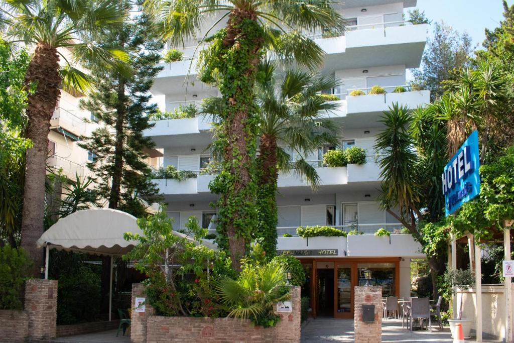 a building with palm trees in front of it at Stefanakis Hotel & Apartments in Varkiza