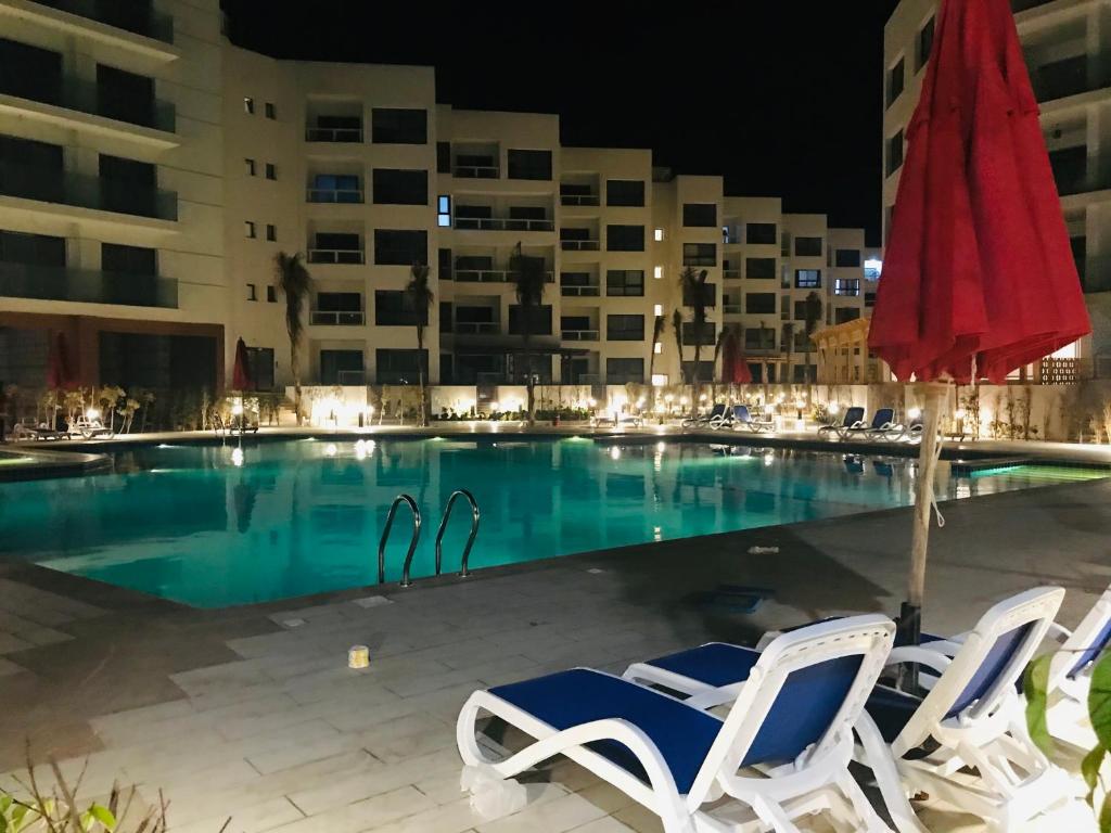 a swimming pool with two chairs and a red umbrella at Porto Said Resort Rentals in Port Said