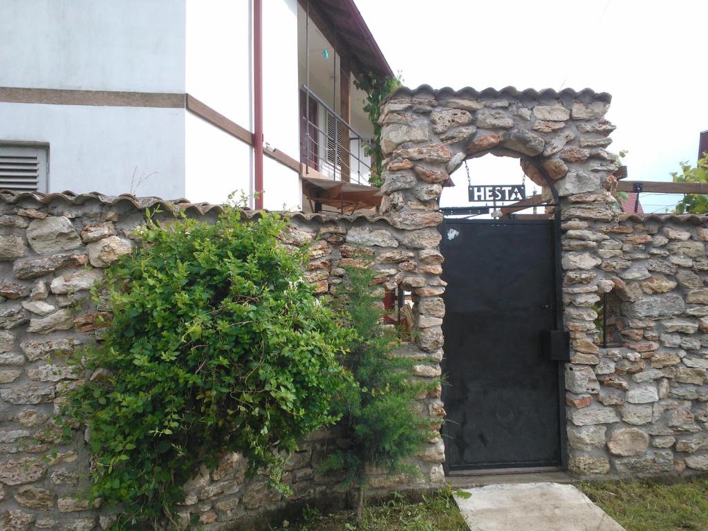 a stone wall with a black door in front of a building at Hesta in Vama Veche