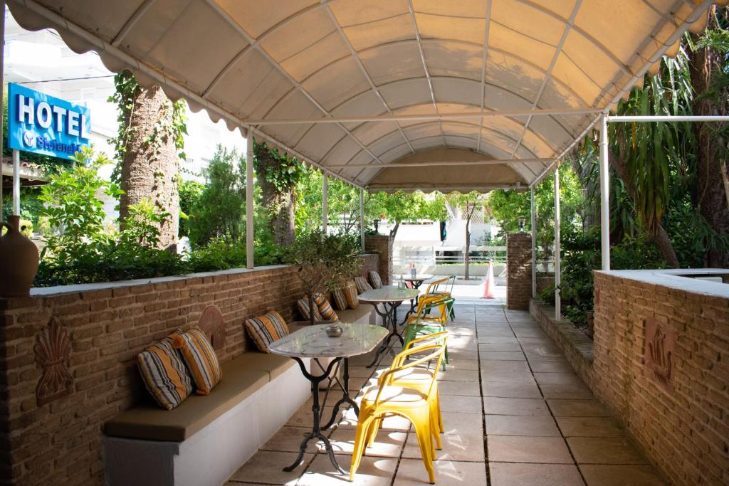 a patio with tables and chairs under an umbrella at Stefanakis Hotel & Apartments in Varkiza