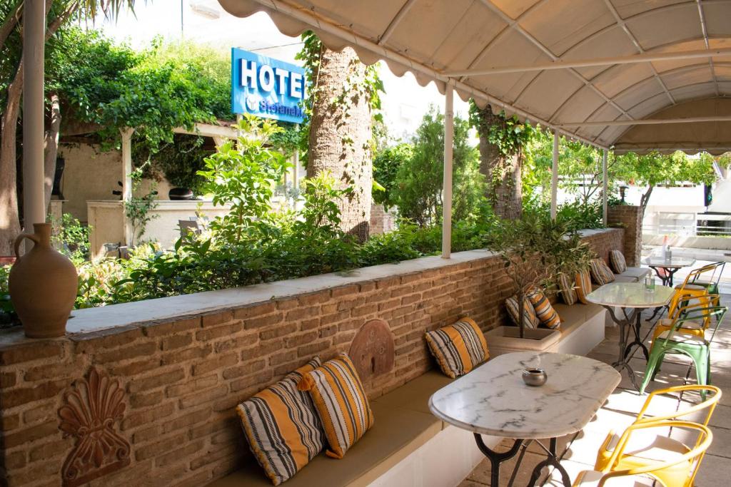a patio with tables and chairs and a brick wall at Stefanakis Hotel & Apartments in Varkiza