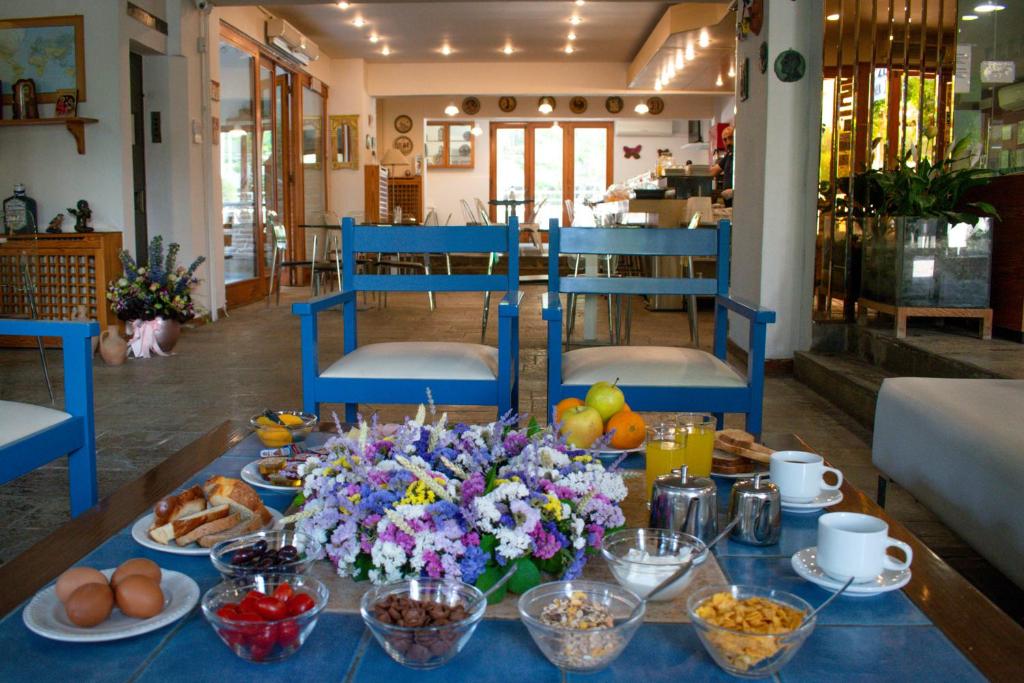 a table with breakfast foods and flowers on it at Stefanakis Hotel & Apartments in Varkiza