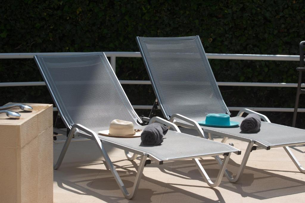 two lawn chairs with hats on them on a patio at Stefanakis Hotel & Apartments in Varkiza