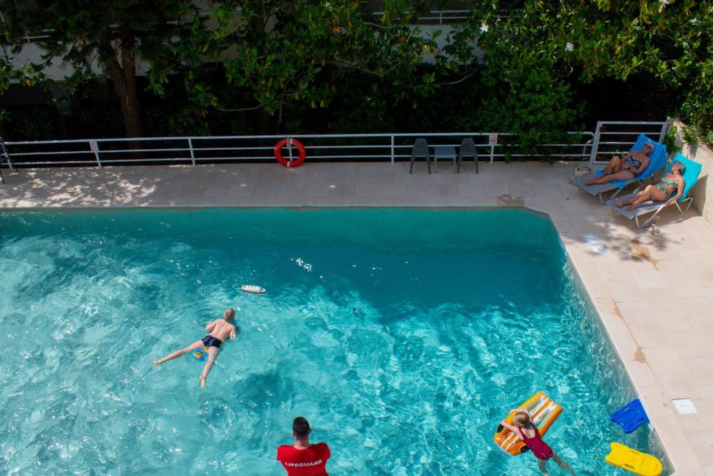 Dos personas están nadando en una piscina en Stefanakis Hotel & Apartments en Varkiza
