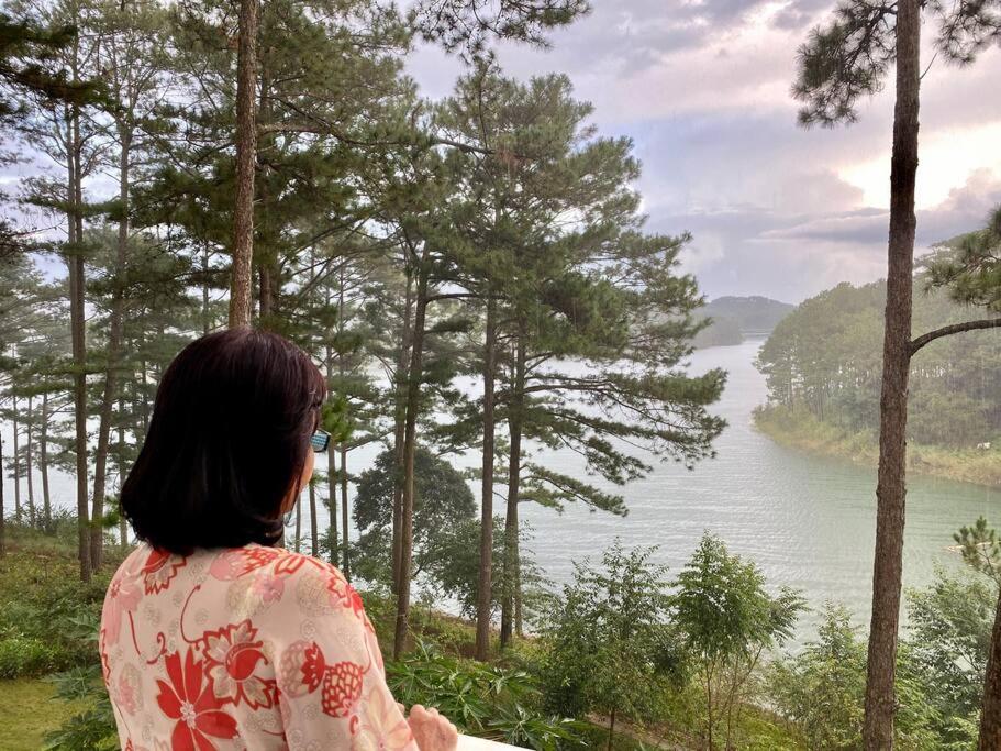 a woman looking out at a lake with trees at The Dream Villa Best Lake View in Xuan An