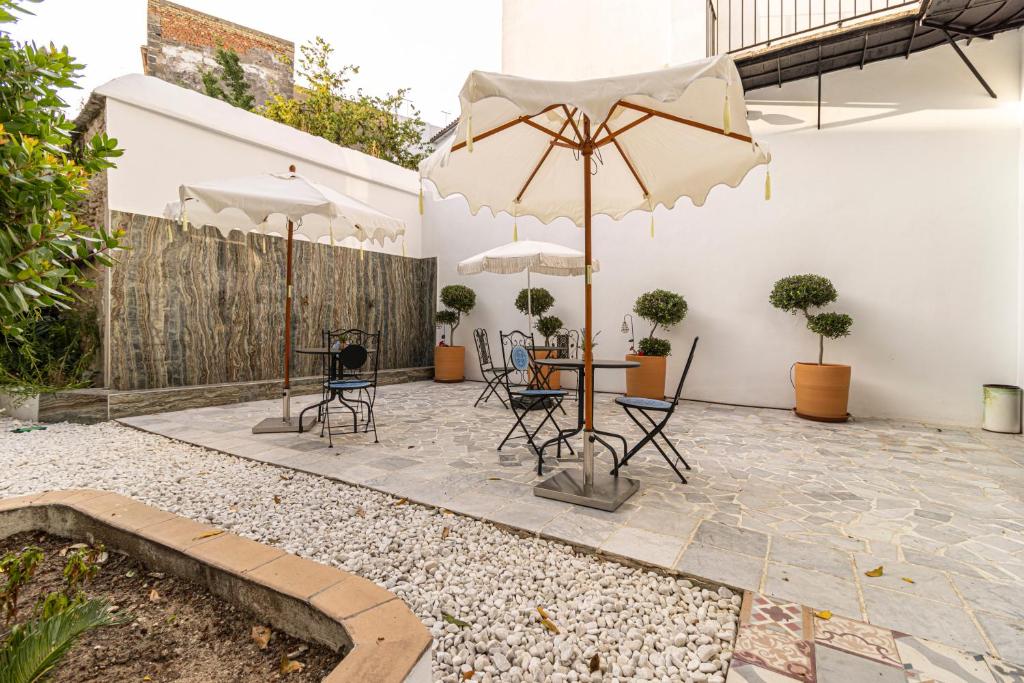 a patio with a table and chairs and umbrellas at Casa Palacio Rufina & Jardines in Jerez de la Frontera