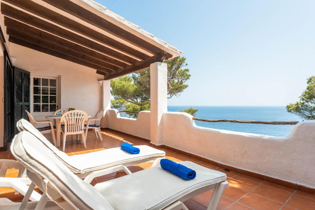 a patio with chairs and a table and the ocean at Vista Mar in Cala Galdana
