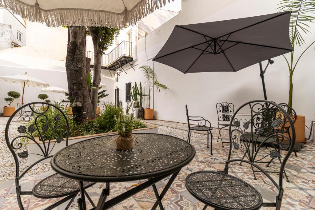 a patio with a table and chairs and an umbrella at Casa Palacio Rufina & Jardines in Jerez de la Frontera