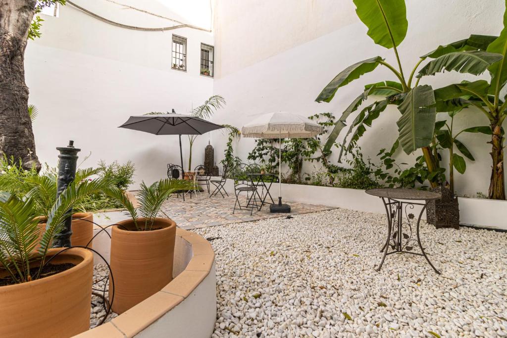 a courtyard with plants and tables and an umbrella at Casa Palacio Rufina & Jardines in Jerez de la Frontera