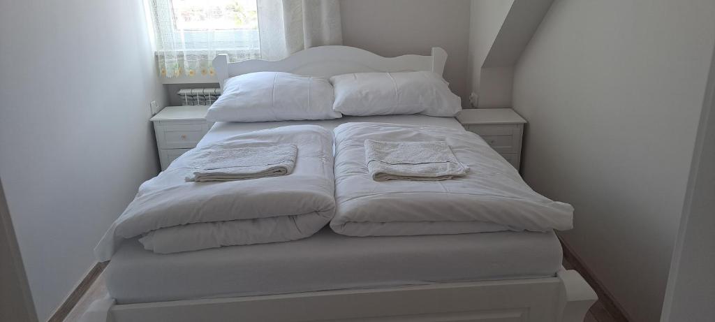 łóżko z białymi kocami i poduszkami w obiekcie Apartament Magurka 1 w mieście Rycerka Górna