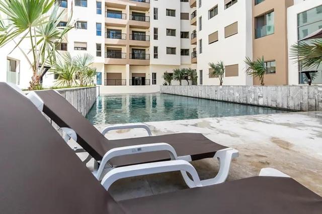 una piscina con sillas y una mesa frente a un edificio en THE luxurious and romantic pearl apartment, en Mohammedia