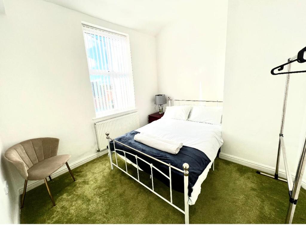 a bedroom with a bed and a chair and a window at Home in Nottingham in Nottingham