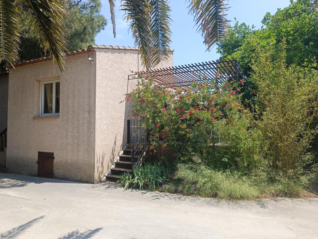 un edificio con una escalera junto a un arbusto con flores en Gîte Rosa et Jean-Jacques en Aigues-Mortes