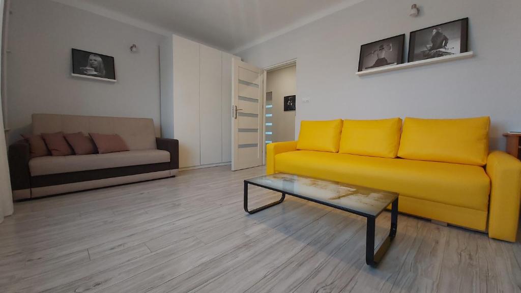 een woonkamer met een gele bank en een salontafel bij Apartament w Centrum in Sandomierz