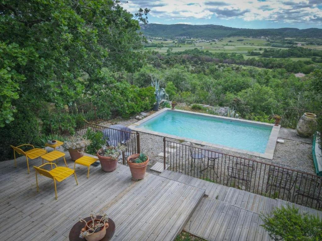 een terras met een zwembad en een tafel en stoelen bij Le petit Mas in Vogüé