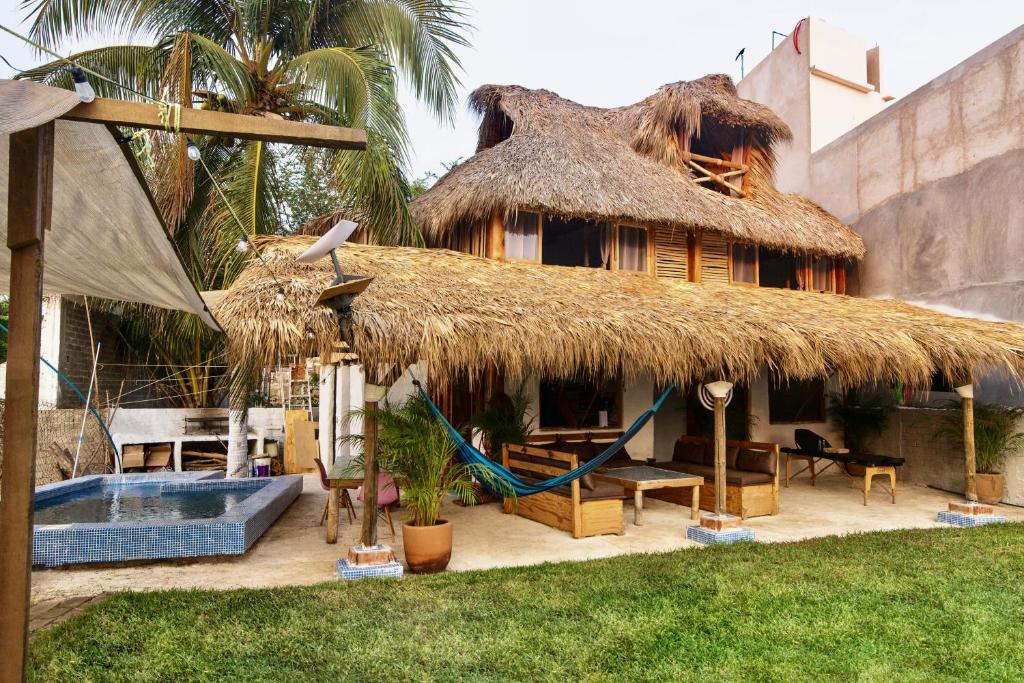 a building with a straw hut with a swimming pool at Emuna Guest house in Puerto Escondido