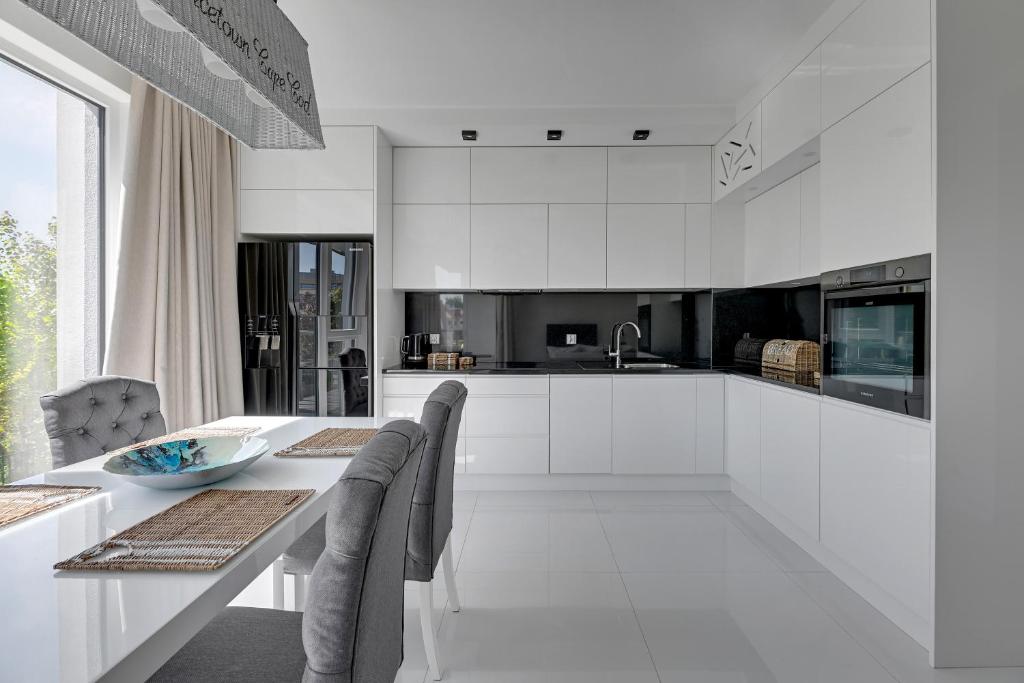 biała kuchnia ze stołem i krzesłami w obiekcie Grand Apartments - Apartament Tre Mare - By the sea w Gdańsku