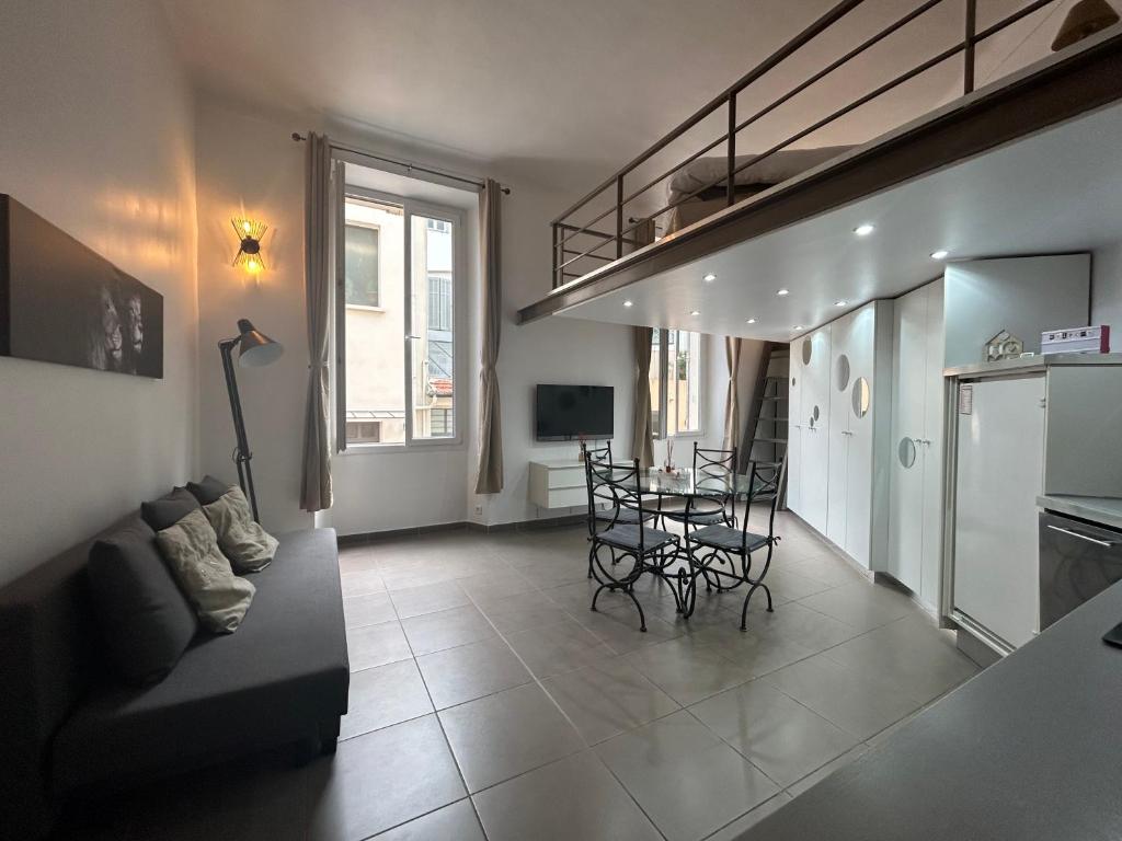 un salon avec un canapé et une table avec des chaises dans l'établissement Charmant studio centre ville Cannes, à Cannes