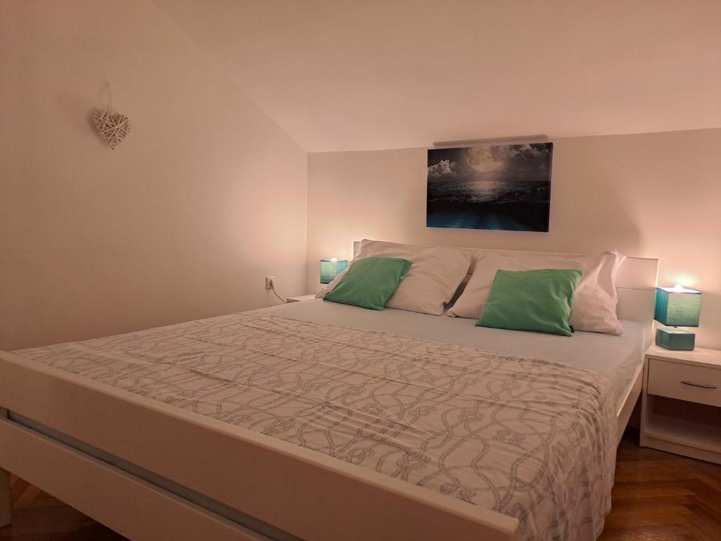 a bedroom with a large bed with two green pillows at Son de Mar Novalja-Pag Apartment in Novalja