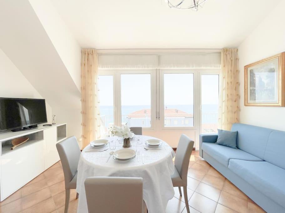 uma sala de estar com uma mesa e um sofá azul em [Attico vista mare] ascensore in casa - WiFi - parcheggio gratis em Borghetto Santo Spirito