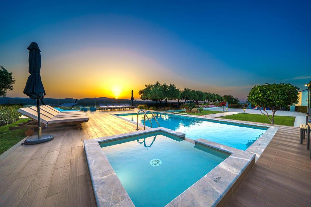 a large swimming pool with a sunset in the background at Mythic Olive villa - Heated Pool - Amazing view in Perivólia