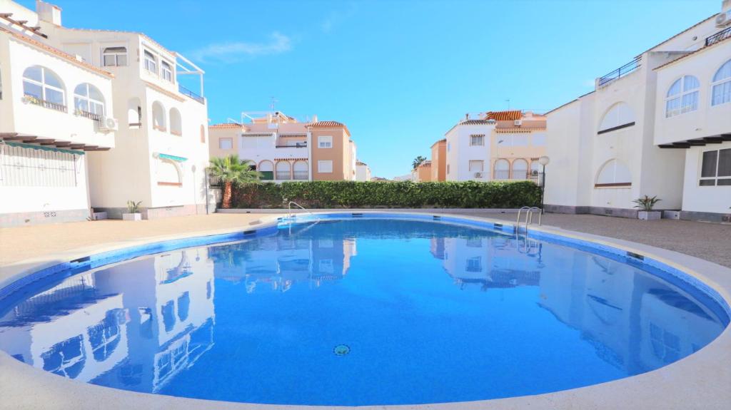 een groot blauw zwembad met gebouwen op de achtergrond bij Sea Apartment 4082 in Torrevieja