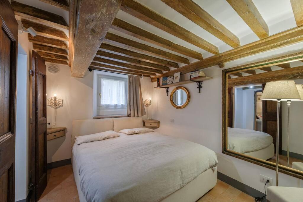 een slaapkamer met een groot bed en een spiegel bij La Finestrella in Cortona