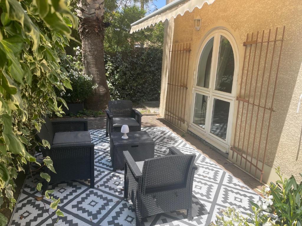 a patio with chairs and tables and a tree at Hôtel Ulysse Montpellier Centre in Montpellier