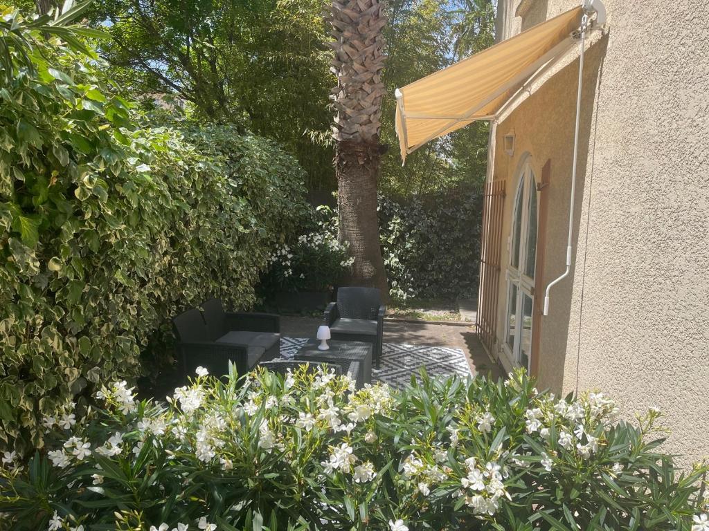 a patio with chairs and an umbrella and some flowers at Hôtel Ulysse Montpellier Centre in Montpellier