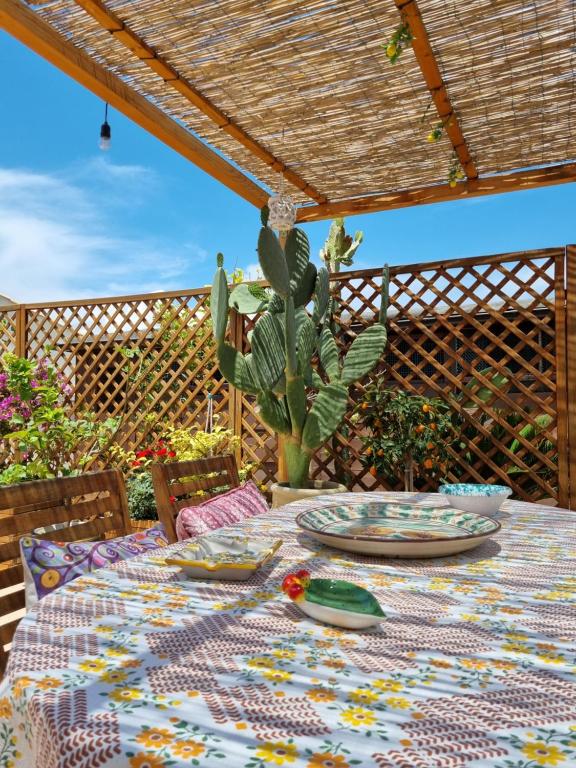 una mesa con platos y un cactus en un patio en La Dimora di Helios, en Noto