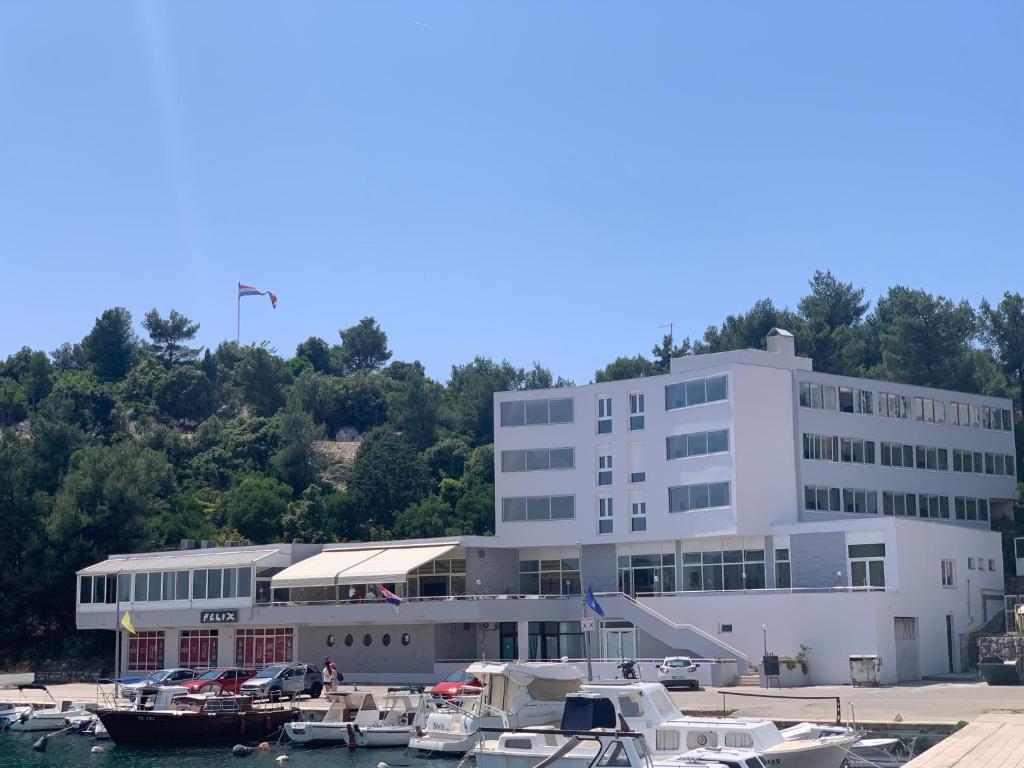 un grand bâtiment blanc avec des bateaux dans un port de plaisance dans l'établissement Hotel Tolero, à Ploče