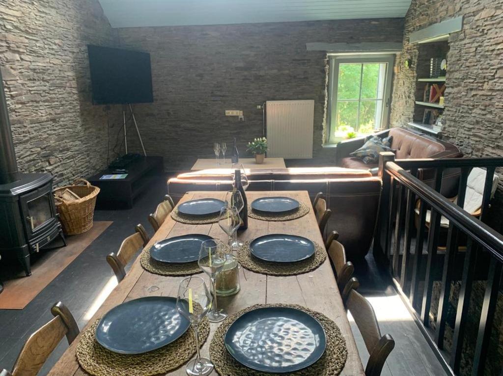 een houten tafel met borden en wijnglazen erop bij La Maison Ardoise in Herbeumont