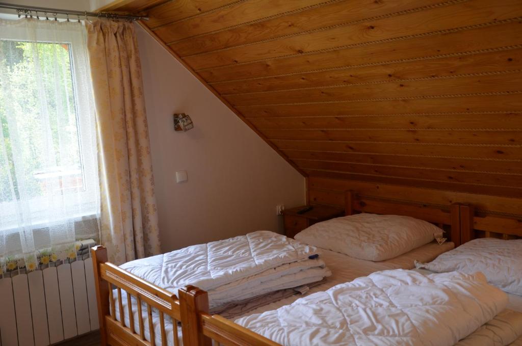 2 bedden in een slaapkamer met een houten plafond bij Magurka Rycerka Górna in Rycerka Górna