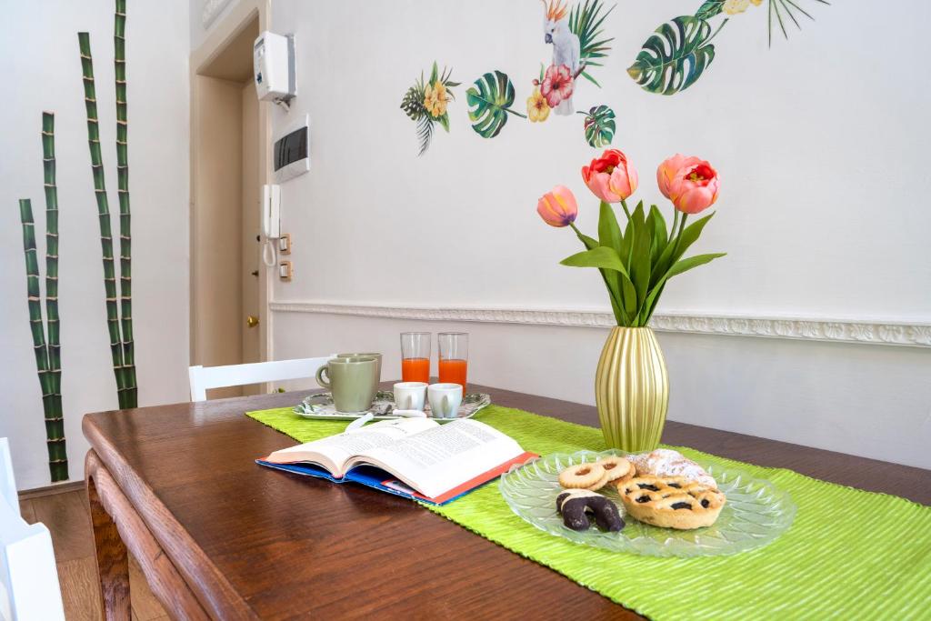 uma mesa com um livro e donuts e um vaso com flores em La Bombetta Cheerful Apartment em Bari