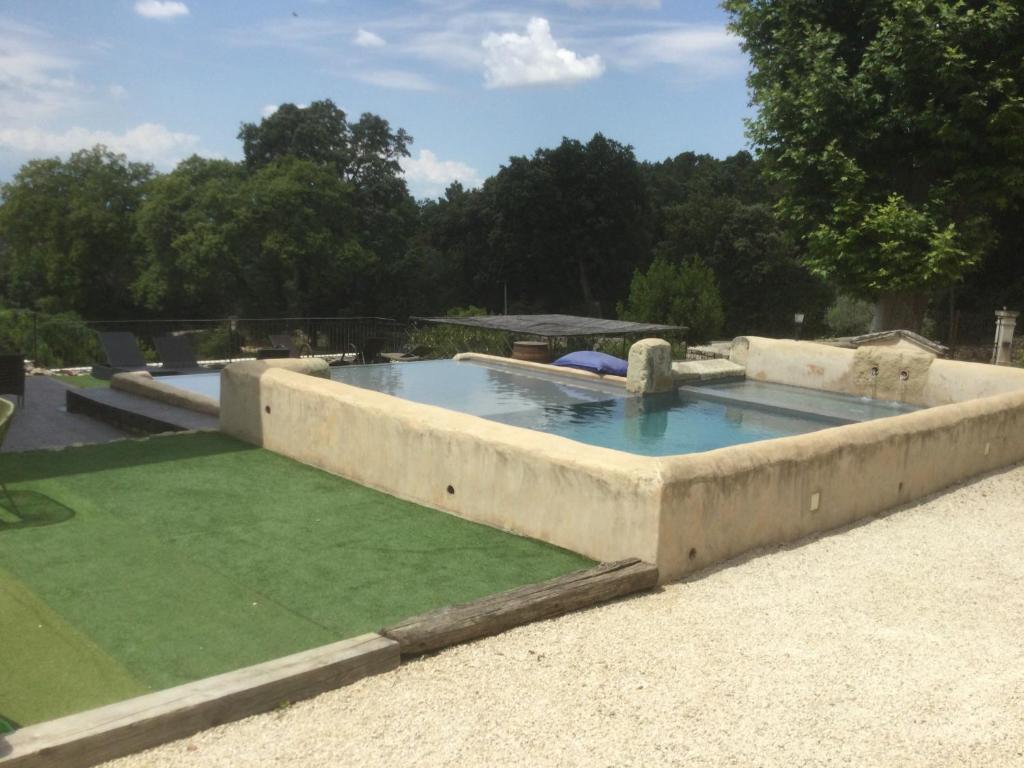 une grande piscine en béton entourée d'une pelouse verte dans l'établissement Bâtisse dans un domaine provençal, à Bollène