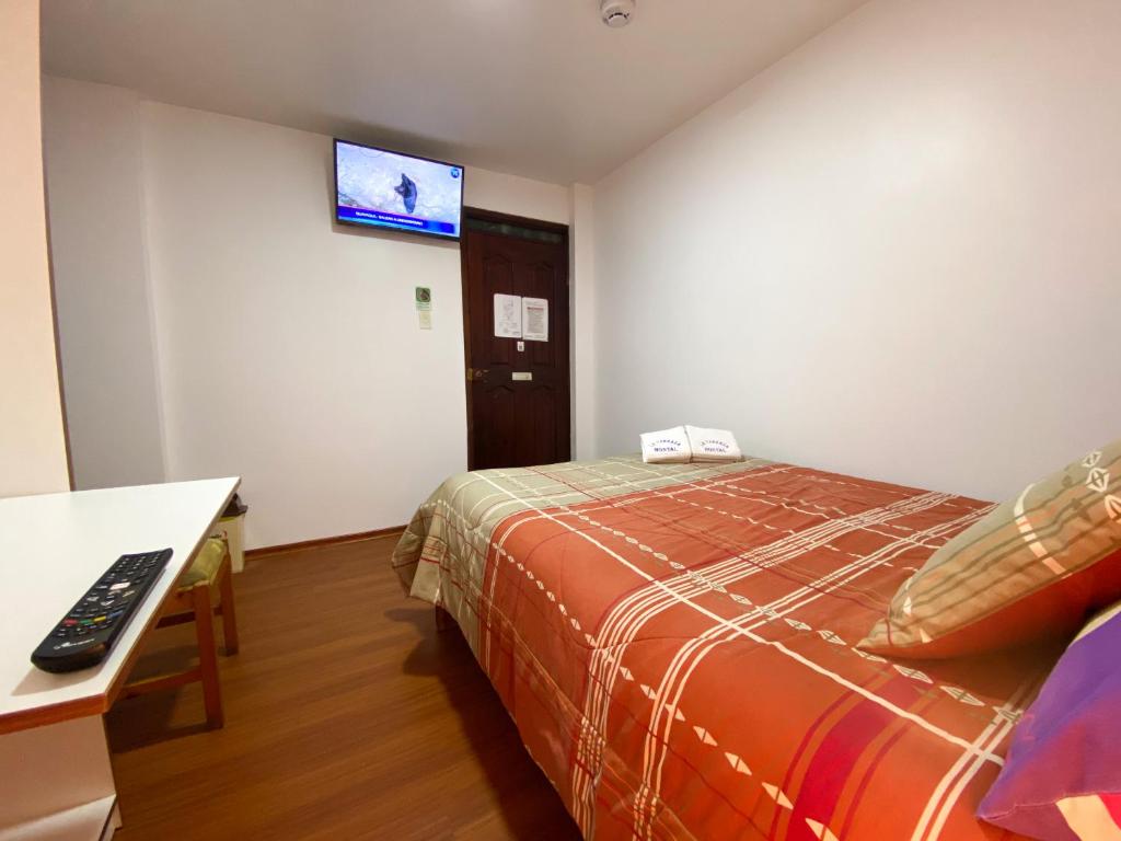 Habitación de hotel con cama y TV en la pared en Hostal La Terraza en Quito