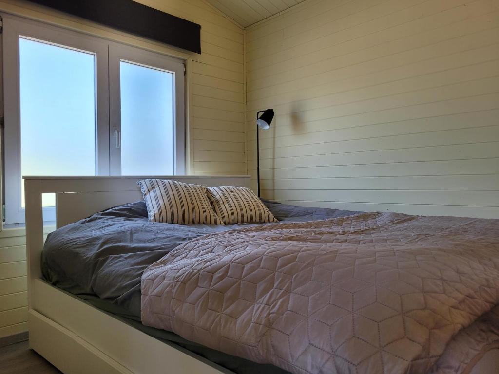1 dormitorio con 1 cama en una habitación con ventana en Rustig gelegen chalet Solvo met terras aan het water, en Geel