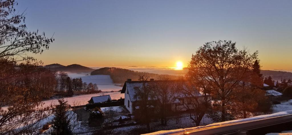 a sunrise over a snowy field with the sun in the distance at Ferienwohnung Schauenburg in Schauenburg