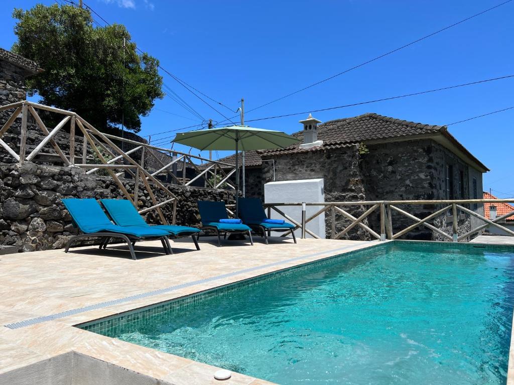 une villa avec une piscine et deux chaises bleues dans l'établissement Gouveia Cottage by AnaLodges, à Seixal