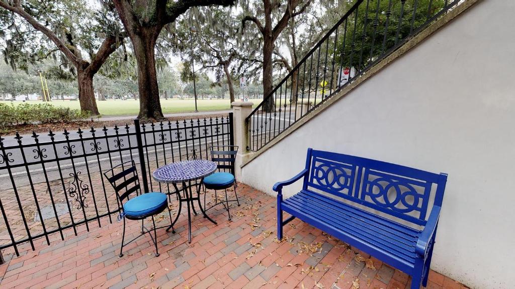 um banco azul e uma mesa e cadeiras ao lado de uma cerca em Suite Escape em Savannah