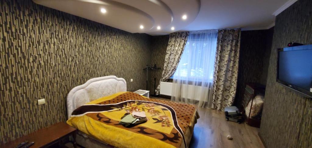 una camera con un letto con una coperta gialla e una TV di Апартаменти a Truskavec'