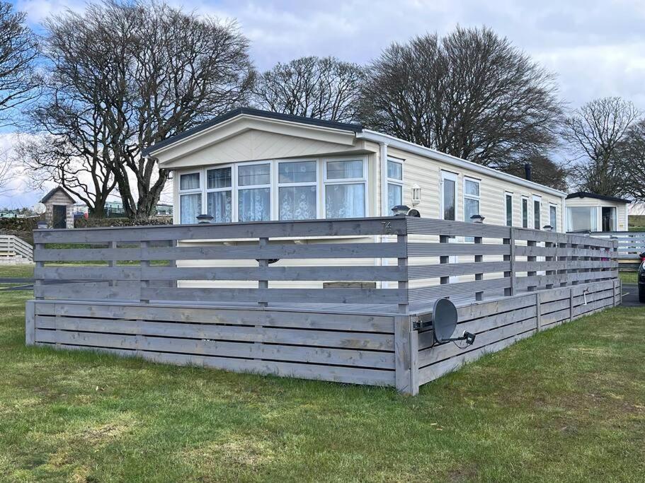 a house with a large wooden fence in a yard at Heron View Holiday Home in Balminnoch