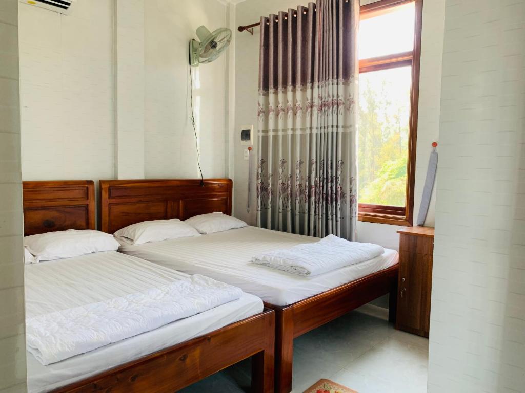 2 camas individuales en una habitación con ventana en Nhà Nghỉ Relax Cảnh Dương, en Lang Co