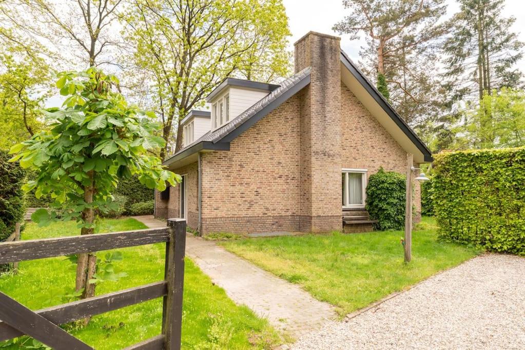 a brick house with a fence in front of it at Grote vakantiewoning 190m2! op ruim- en groen perceel in Otterlo