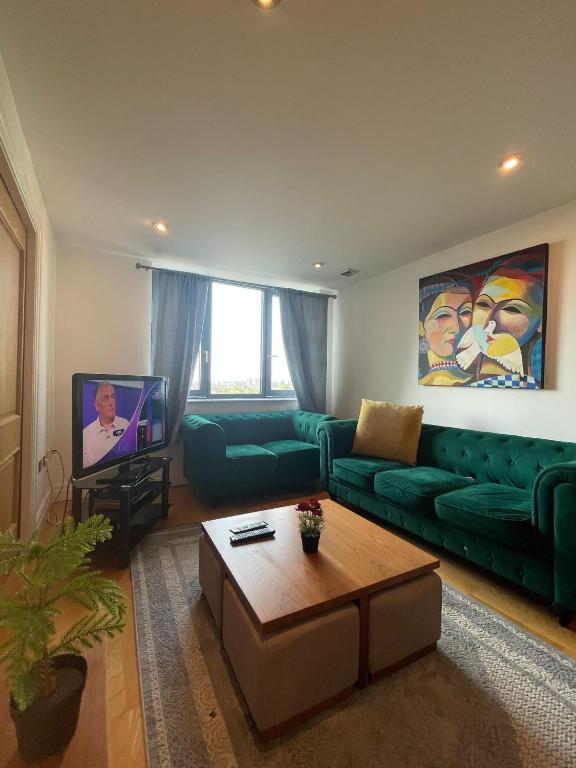 a living room with a green couch and a tv at Super Modern 3-Bedroom Apartment in London