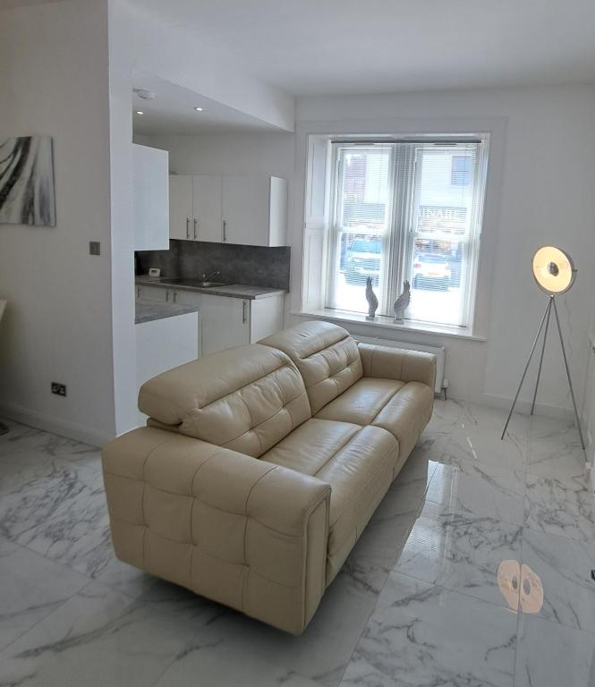 a living room with a leather couch and a kitchen at Maze 21one Apartment in Ayr