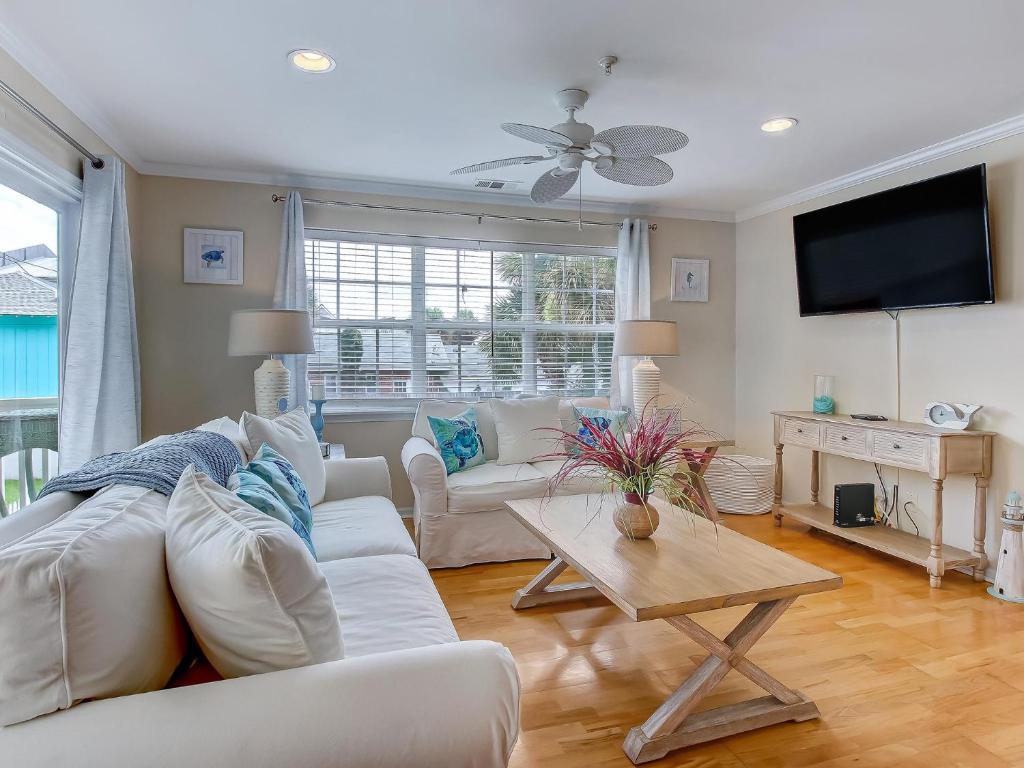 a living room with white furniture and a flat screen tv at Silver Sands in Tybee Island