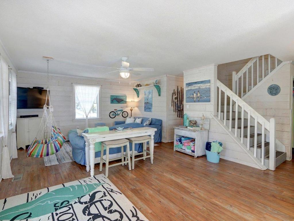 a living room with a staircase and a table at Barefoot Children in Tybee Island