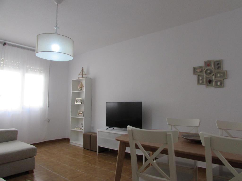 sala de estar con TV, mesa y sillas en GARRUCHA SWEET HOME, en Garrucha