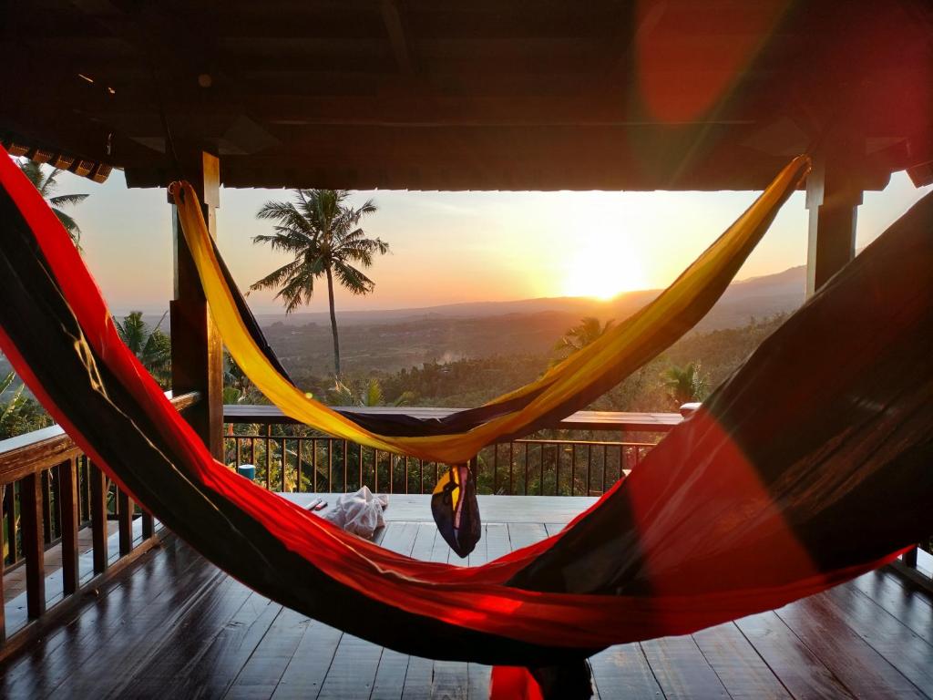 two hammocks on a deck with the sunset in the background at D'kailash Retreat in Singaraja